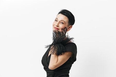 Elegant woman in black dress posing with hands on face and gazing off to the side