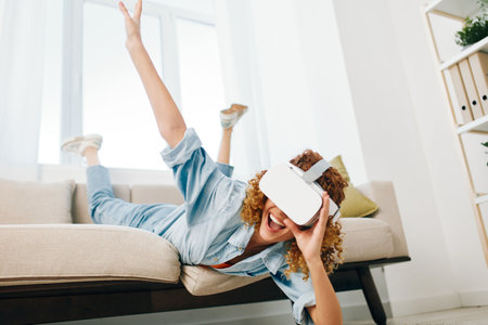 Futuristic Joy: A Young Woman Smiling with Excitement while Using Virtual Reality Glasses in her Modern Living Roomの写真素材