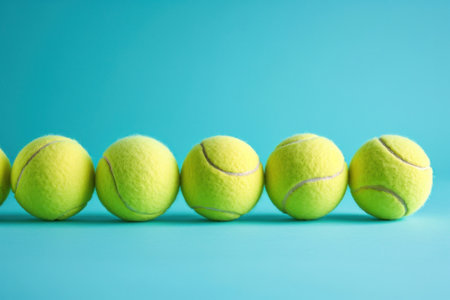 Row of tennis balls on blue background with copy space for textの素材
