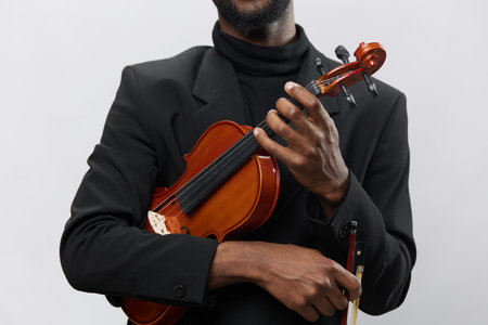 Elegant black man in suit holding violin on white background, creative concept of music and diversityの写真素材
