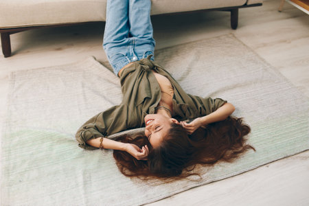 Carefree Woman Relaxing on a Cosy Sofa in a Modern Apartmentの写真素材