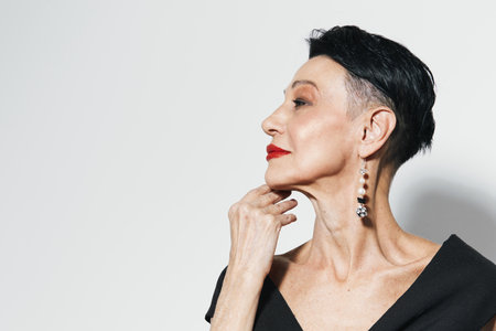 Portrait of a young woman with short hair and red lips looking off to the side with hand on chin