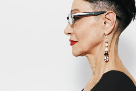Portrait of a mature woman with short hair and elegant earrings on her earlobes, looking confident and stylishの写真素材