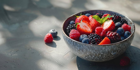 Fresh mixed berries in a white bowl on a rustic wooden table top view, with copy space for textの素材