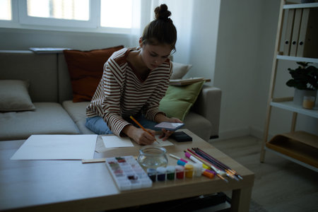 Happy Teenage Girl, an Artist, Painting on Easel at Home: Indoor Creativity and Leisure.の写真素材