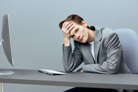 Tired Businessman at Desk; Overworked Employee with Headache; Stressful Work Environment; Office Burnout Concept; Frustrated Worker in Office Settingの写真素材