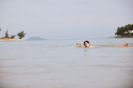 Smiling Asian Man Enjoying Active Water Sports on a Tropical Beach Vacationの写真素材