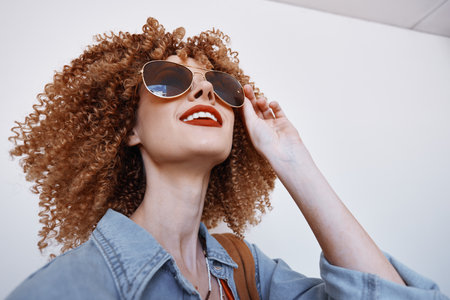 Joyful Beauty: Smiling Woman with Curly Hair and Goggles, Expressing Fun and Happiness in Fashionable Eyeglassesの写真素材