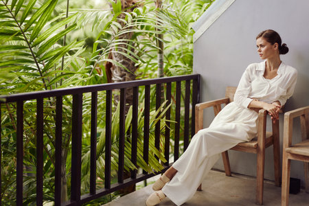 Happy Woman Relaxing on a Tropical Balcony Smiling in the Sunlight with Trendy Sunglasses, Enjoying a Vacation and the Freedom of a Relaxing Lifestyleの写真素材