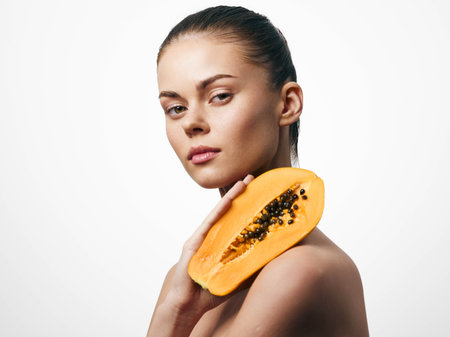 Beautiful young woman holding papaya fruit in her hand on a white background, healthy lifestyle conceptの写真素材