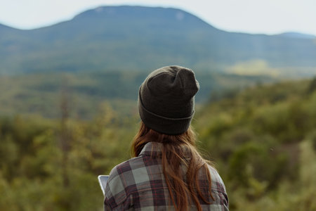 Woman in Plaid Shirt and Beanie Admiring Majestic Mountain Range During Outdoor Adventure Travel Explorationの写真素材
