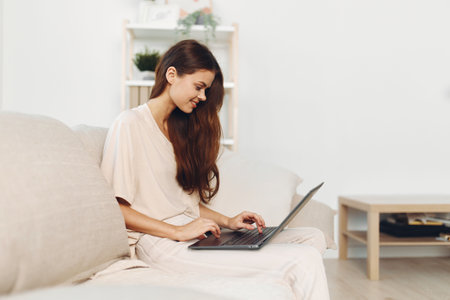 Smiling Woman Using Laptop in Cozy Home Office: Freelance Lifestyleの写真素材