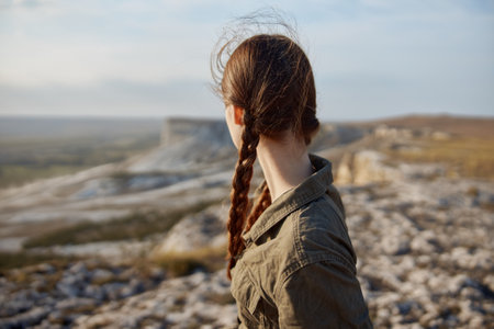 Woman with braids standing on hill overlooking valley in travel destination beauty spotの写真素材