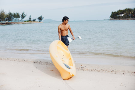 Happy Asian Man Kayaking on Tropical Beach: Summer Vacation Funの写真素材