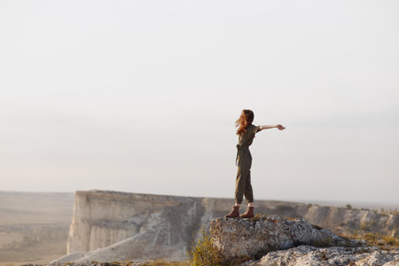 On top of the world woman embracing freedom and adventure in nature on mountain summit with arms outstretchedの写真素材