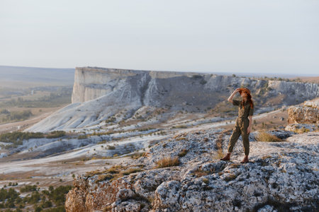Woman standing on cliff overlooking valley with majestic mountain view on travel adventure tripの写真素材