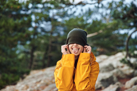A woman in a yellow jacket experiencing the breathtaking beauty of nature while standing on a mountaintopの写真素材