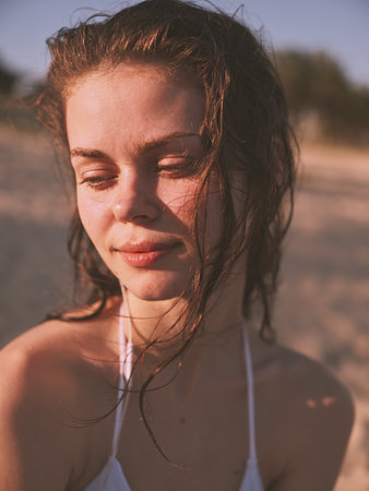 Serene young woman with closed eyes and blowing hair enjoying a peaceful moment on the beachの写真素材