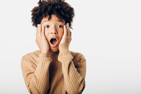 Astonished young african american boy with wide eyes and open mouth expressing surprise, isolated against a white backgroundの写真素材