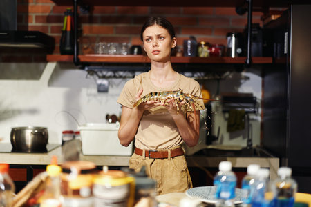 Woman Holding Lobster in Kitchen Setting with Counter Backgroundの写真素材