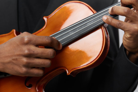 Close up of man in suit playing violin on white background, artistic performance concept for music and elegance themeの写真素材