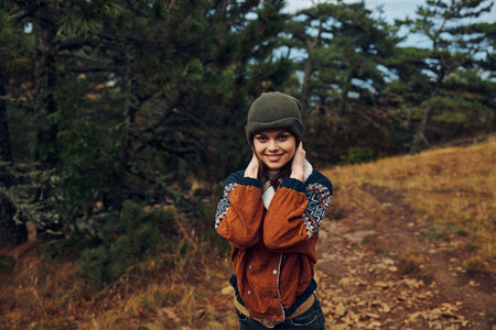 Happy young woman smiling on a scenic autumn hiking trail through the forest surrounded by colorful foliageの写真素材