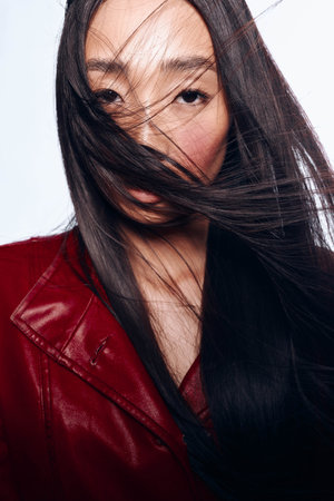Beautiful woman with long black hair blowing in the wind against a clear blue sky backgroundの写真素材