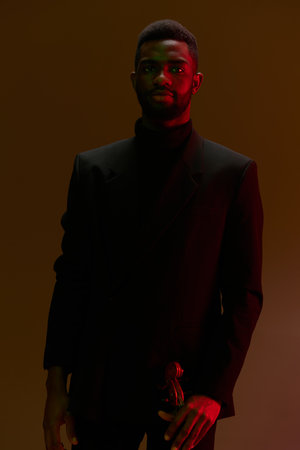 Businessman in formal attire standing in front of vibrant red light, creating a bold and dramatic...