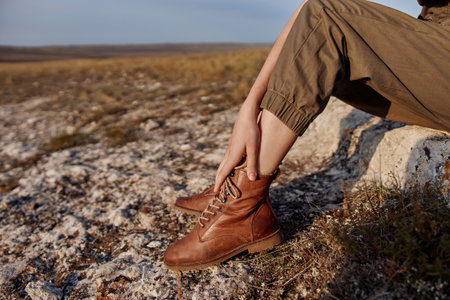 Woman sitting on top of rock in brown boots with crossed legs travel adventure beauty in nature...