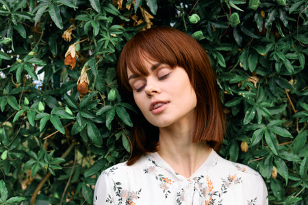 Tranquil woman standing by lush green bush with eyes closed in peaceful meditation