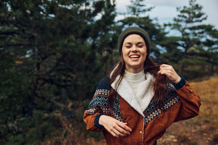 Smiling young woman enjoying autumn nature in the forest, outdoor portrait of beauty and travel...
