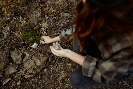 A Woman Engaged in Spiritual Meditation with Small Object Near Rock Pile on Ground in Nature