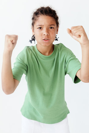 Confident young boy in stylish outfit flexing fists in a trendy fashion pose on green backgroundの写真素材