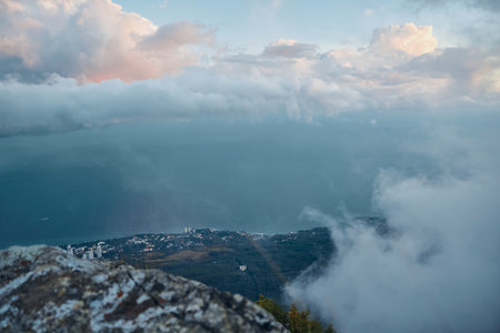 Magnificent view of the turbulent ocean and dramatic clouds from the peak of a mountain on a foggy...