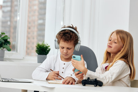 Happy siblings enjoying online gaming together on their smartphones, capturing the moment with a...