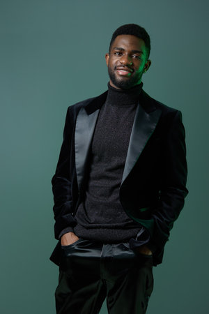 Confident black man in stylish black turtleneck and suit posing with poise and elegance