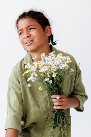 Innocent joy young boy holding a bunch of daisies against a clean white backgroundの写真素材