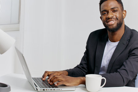 African american businessman working on laptop at desk in modern office environment