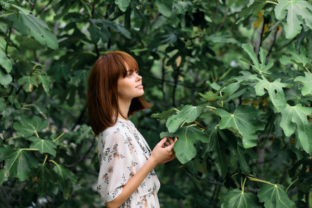 Serene woman standing gracefully in front of a lush green tree with vibrant leaves