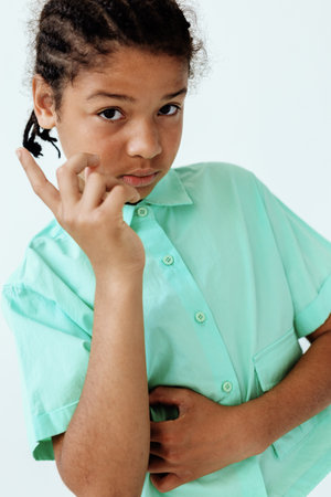 Young african american boy in green shirt playfully shushing while holding finger to lips