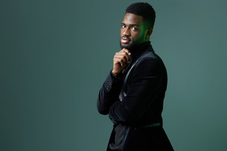 Confident african american man in elegant black suit posing against vibrant green backdrop