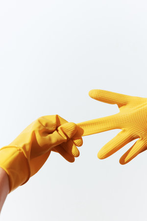 Two hands in yellow rubber gloves reaching out to each other on a white backgroundの写真素材