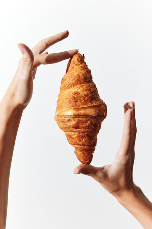 Hands holding a heartshaped croissant on white backgroundの写真素材