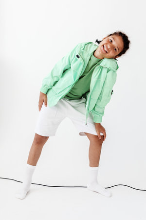 Confident young boy in stylish outfit striking a pose in front of a minimalist white backgroundの写真素材