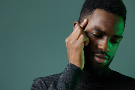 African american man in black sweater holding head, appearing thoughtful or concerned, isolated on a...
