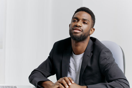 Confident businessman in a suit sitting at desk with hands on hips in modern office setting