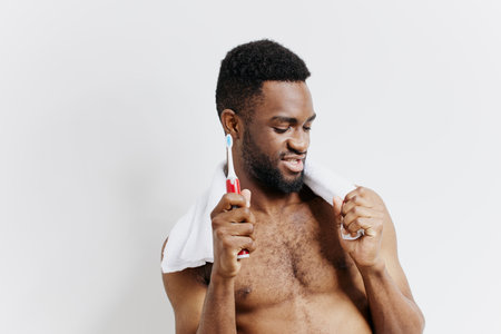 Morning routine shirtless man brushing teeth against white backgroundの写真素材