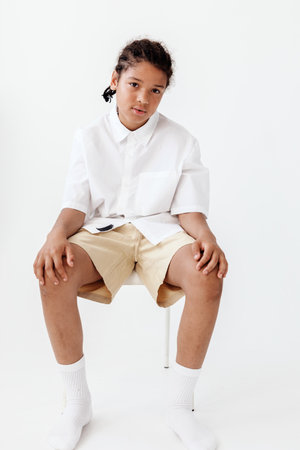 Portrait of a stylish young boy relaxing in minimalist white room with modern decor