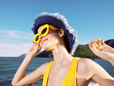 Beach woman wearing sunglasses and hat with ocean backdrop, distant mountainsの写真素材