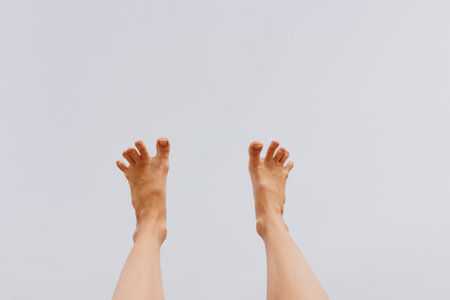 Bare feet in the air against a gray sky background, with copy space in the top left cornerの写真素材